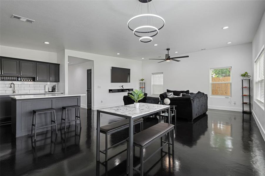 Kitchen with a kitchen bar, ceiling fan with notable chandelier, a center island, hanging light fixtures, and backsplash