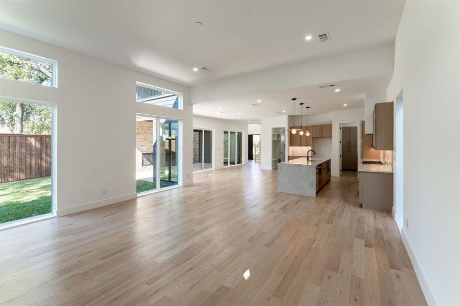 Unfurnished living room with a high ceiling, light wood-type flooring, and sink