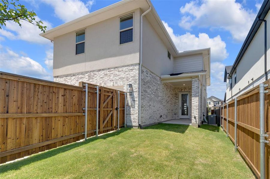 Manicured backyard with a wooden privacy fence and a rear covered patio