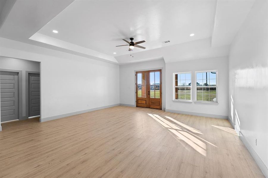 Unfurnished room with a tray ceiling, light wood-type flooring, recessed lighting, and a ceiling fan