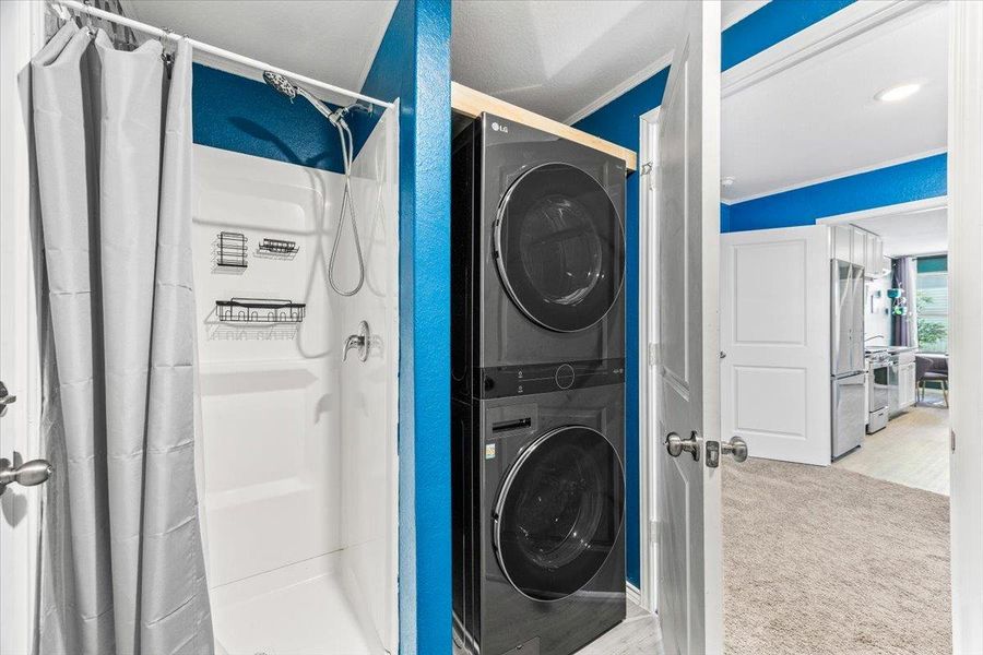 Laundry room featuring stacked washer and clothes dryer and light carpet Laundry room featuring stacked washer and clothes dryer and light carpet