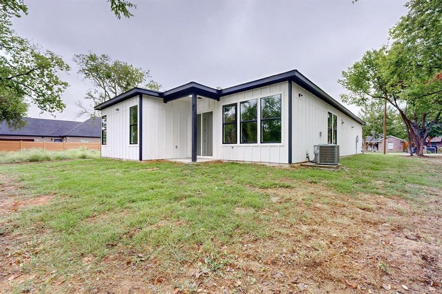 Back of property with cooling unit and a yard