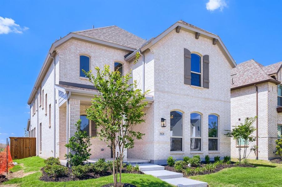 White brick exterior featuring dark shutters, arched windows, a covered front porch, and a concrete walkway