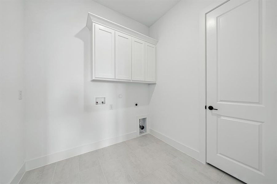 Laundry room featuring gas dryer hookup, cabinet space, hookup for an electric dryer, hookup for a washing machine, and light tile patterned flooring