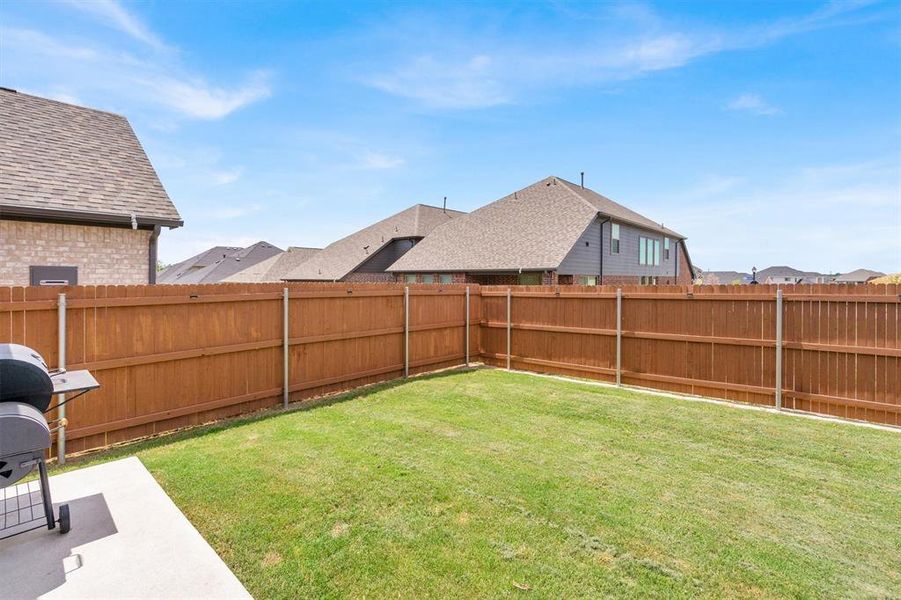 Expansive backyard featuring a manicured lawn, a concrete patio, and a privacy fence