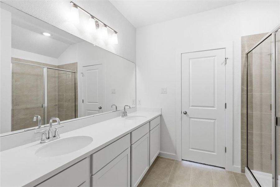 Bathroom featuring double vanity, a shower stall, and light tile patterned floors