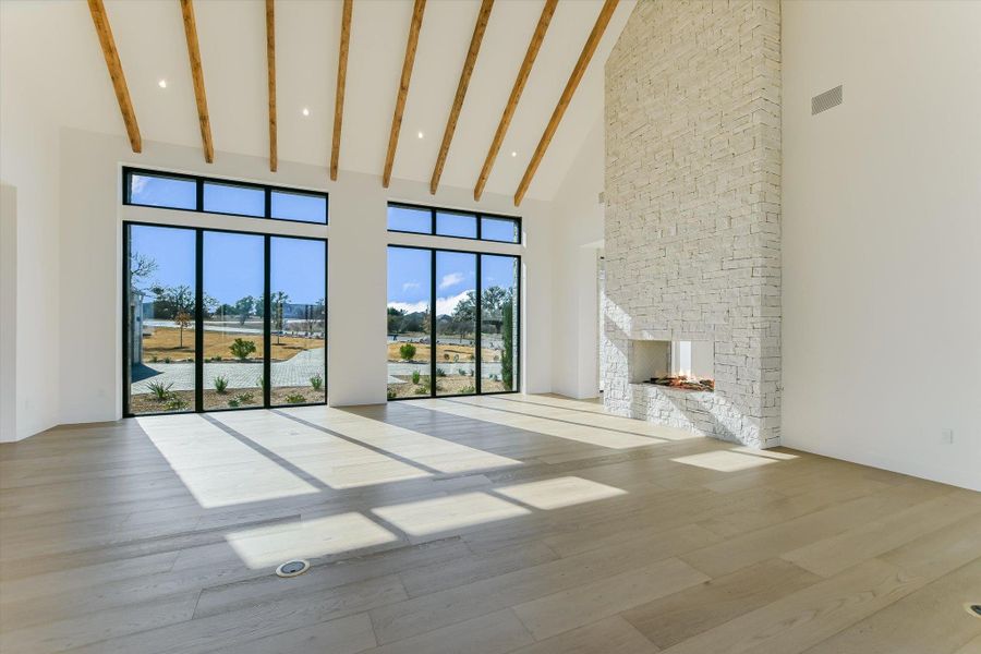Unfurnished living room featuring light wood finished floors, a fireplace, vaulted ceiling, and recessed lighting
