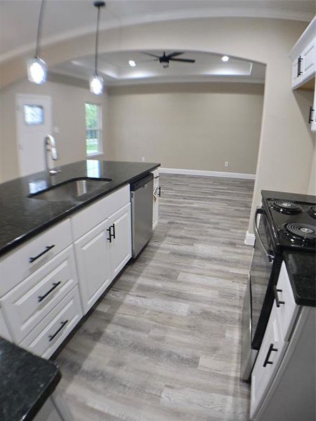 Kitchen featuring white cabinets, dishwasher, light wood-type flooring, and sink