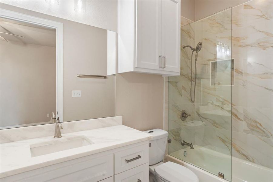 Full bathroom featuring toilet, tiled shower / bath combo, and vanity