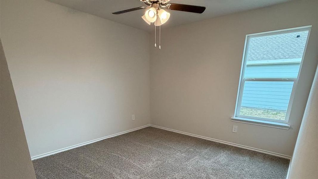 Unfurnished room featuring ceiling fan and dark colored carpet
