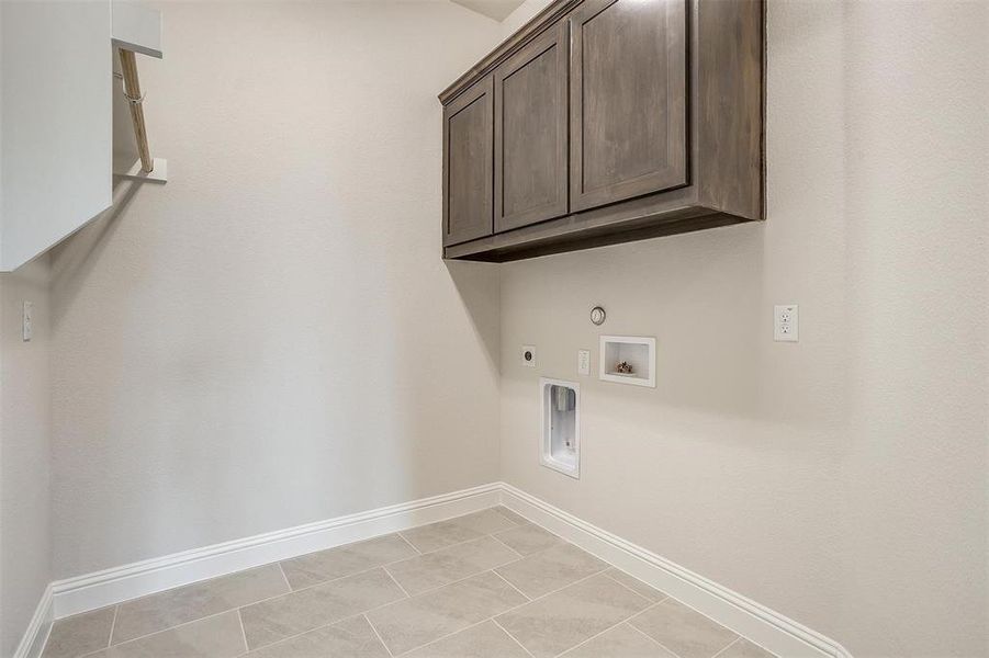 Laundry room with cabinets, electric dryer hookup, light tile patterned flooring, and gas dryer hookup