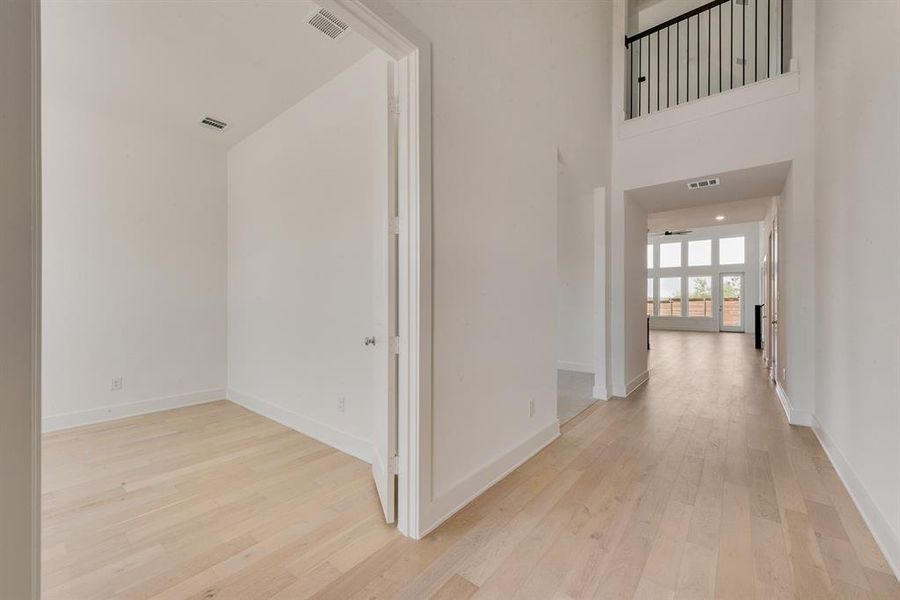 Hall with light wood-style flooring and a towering ceiling Hall with light wood-style flooring and a towering ceiling