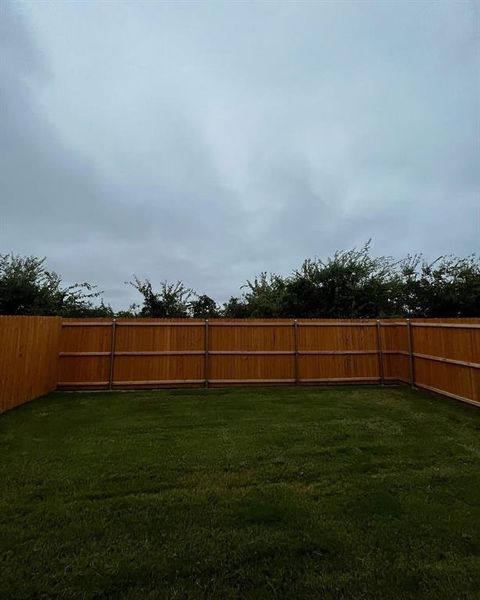 Expansive backyard featuring a lush lawn and perimeter wood fencing Expansive backyard featuring a lush lawn and perimeter wood fencing