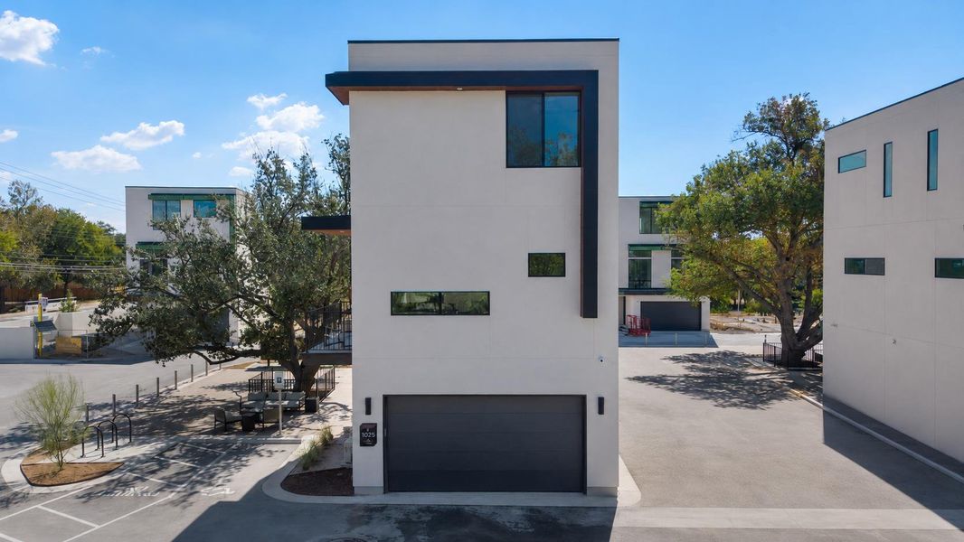Modern facade featuring a dark gray garage door, varied window placements, and a flat roofline with dark trim