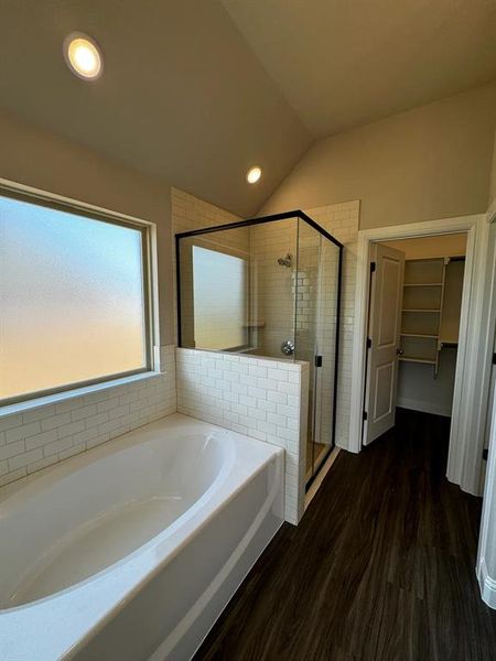 Bathroom with independent shower and bath, vaulted ceiling, and hardwood / wood-style flooring