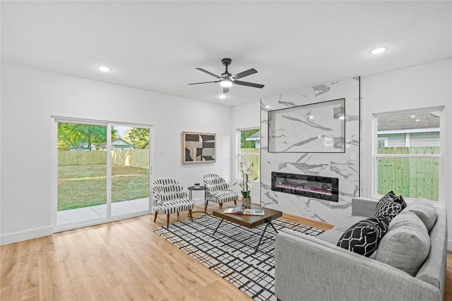 Living room featuring ceiling fan, hardwood / wood-style flooring, and a premium fireplace