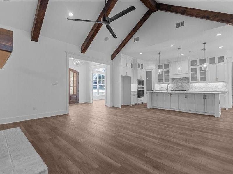 Unfurnished living room with beam ceiling, recessed lighting, dark wood finished floors, a ceiling fan, and high vaulted ceiling