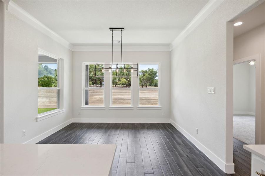 Unfurnished dining area featuring an inviting chandelier, crown molding, and dark wood-type flooring