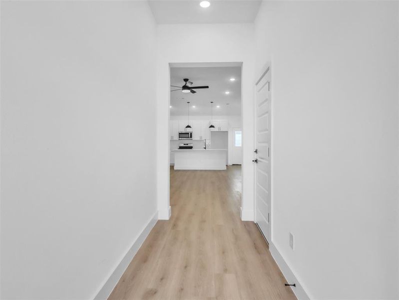 Corridor featuring recessed lighting, light wood-style flooring, and baseboards Corridor featuring recessed lighting, light wood-style flooring, and baseboards