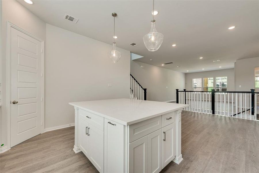 Kitchen featuring a center island, pendant lighting, light wood-type flooring, and white cabinets