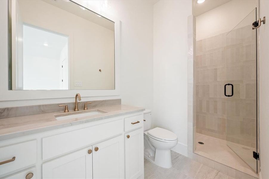 Bathroom with a shower with shower door, vanity, tile patterned floors, and toilet