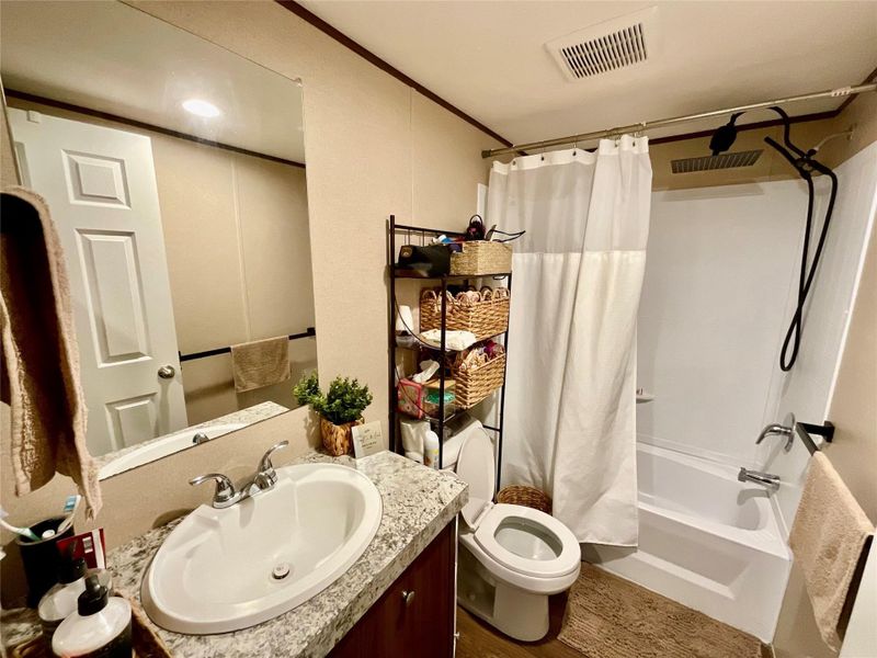 Shared bathroom featuring a white oval sink set in a speckled countertop, chrome faucet, and a large wall-mounted mirror