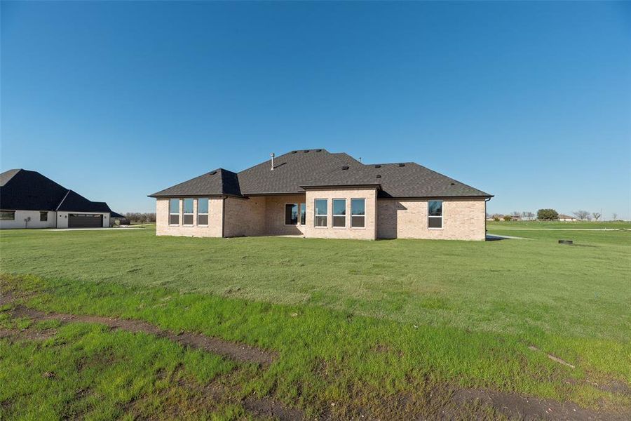 Rear view of house with a lawn, a patio, brick siding, and roof with shingles Rear view of house with a lawn, a patio, brick siding, and roof with shingles