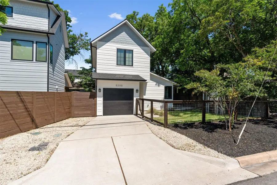 Contemporary two-story residence featuring light siding and a dark garage door. Fully fenced front yard. Contemporary two-story residence featuring light siding and a dark garage door. Fully fenced front yard.