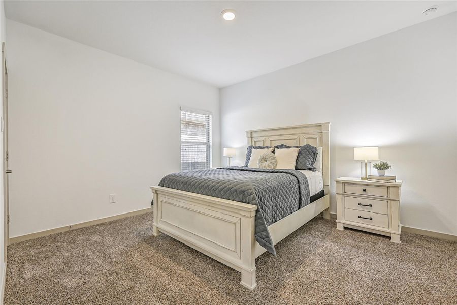 A generously sized secondary bedroom continues the home's light, neutral palette with plush carpet, tall ceilings and a large window providing plenty of natural light. A generously sized secondary bedroom continues the home's light, neutral palette with plush carpet, tall ceilings and a large window providing plenty of natural light.