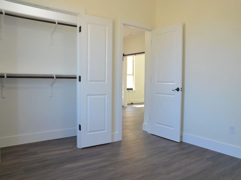 Bedroom with a barn door, dark hardwood / wood-style floors, and a closet