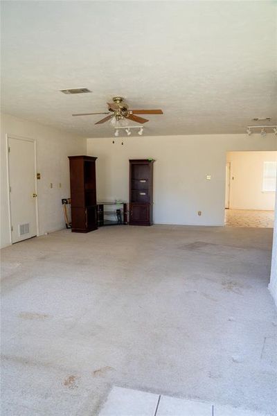 Unfurnished living room with ceiling fan, light colored carpet, and light tile patterned flooring