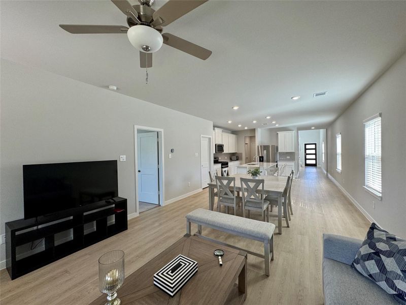 Open-concept living and dining area with a modern kitchen. It features light wood flooring, neutral walls, and ample natural light from several windows. The kitchen is equipped with stainless steel appliances, white cabinetry, and a central island with seating. Open-concept living and dining area with a modern kitchen. It features light wood flooring, neutral walls, and ample natural light from several windows. The kitchen is equipped with stainless steel appliances, white cabinetry, and a central island with seating.