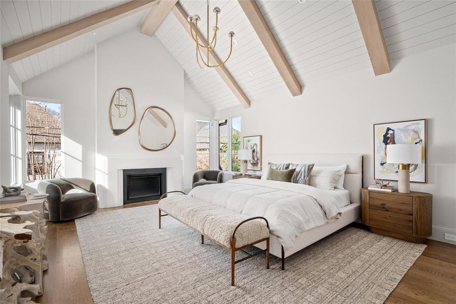 A haven of refined elegance, the primary bedroom is designed to impress with its soaring ceilings and thoughtful architectural details. Overhead, a striking Kelly Wearstler Pedra Two Tier chandelier adds a sculptural focal point, beautifully complementing the stained wood beams and painted tongue-and-groove ceiling. Expansive windows fill the space with natural light, while white oak hardwood floors lend warmth and timeless sophistication to this luxurious retreat.