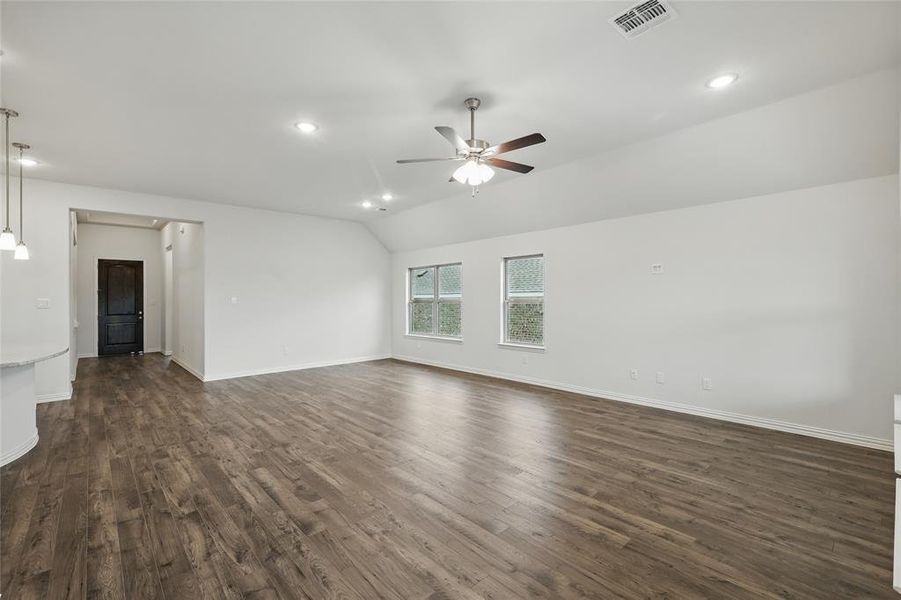 Unfurnished living room featuring visible vents, dark wood-style flooring, baseboards, ceiling fan, and vaulted ceiling Unfurnished living room featuring visible vents, dark wood-style flooring, baseboards, ceiling fan, and vaulted ceiling