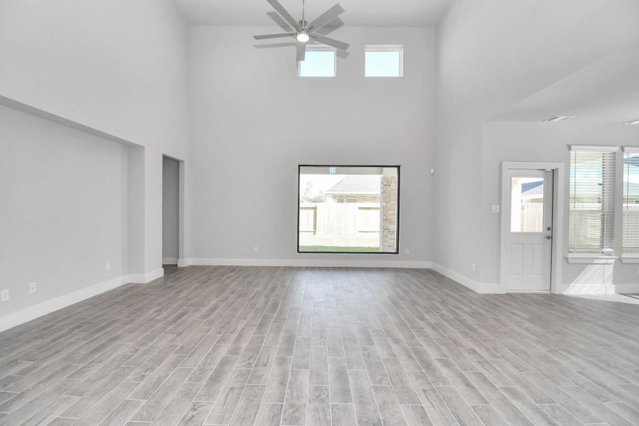 Relax and unwind in this inviting family room, illuminated by abundant natural light streaming in through tall windows, complemented by high ceilings and stunning flooring. Stay comfortable year-round with the gentle breeze from the ceiling fan, creating the perfect atmosphere for family gatherings.