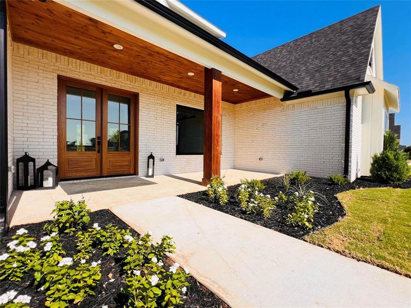 View of exterior entry, large patio, and double doors