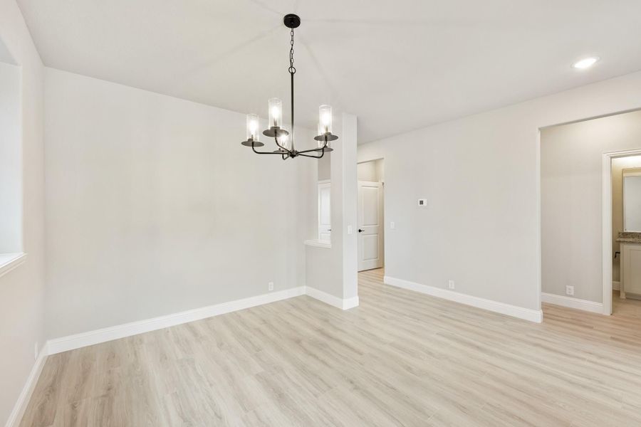 Empty dining room with light wood floors, white walls, and a black five-light chandelier Empty dining room with light wood floors, white walls, and a black five-light chandelier