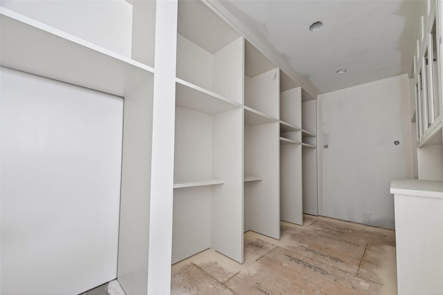 Boutique-style primary closet featuring soaring high ceilings and extensive custom built-in shelving