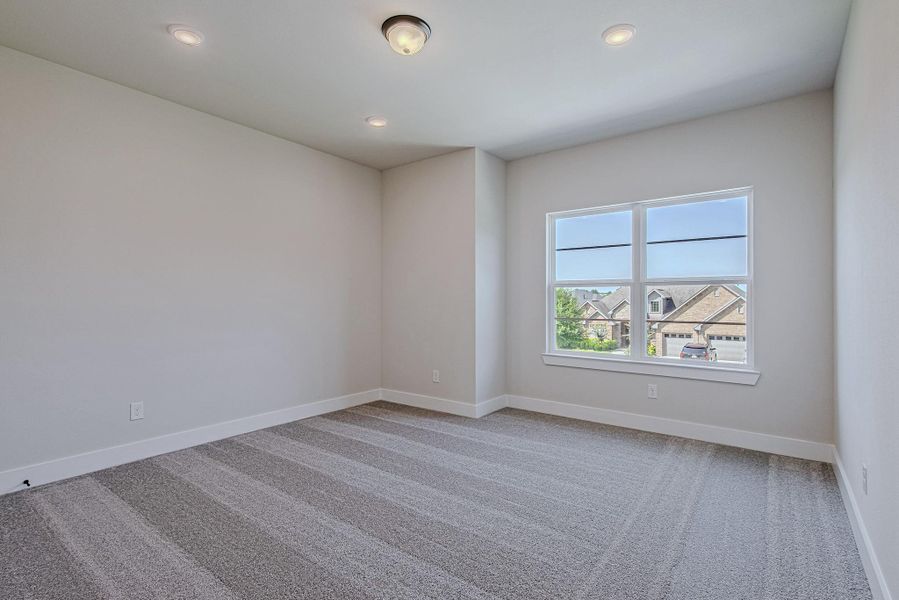 Bright secondary bedroom with carpeted flooring and a large window