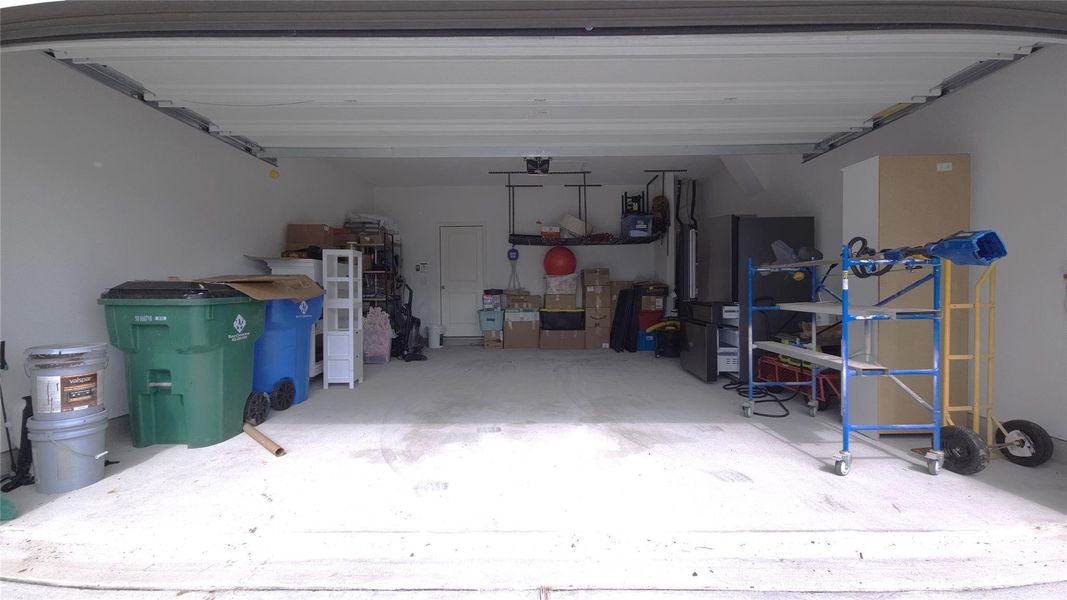 Spacious garage featuring a concrete floor, painted walls, and an overhead garage door
