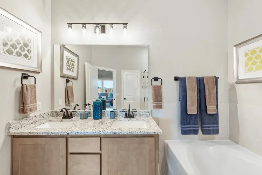 Bathroom with double sink vanity, granite countertop, wood cabinets, and soaking tub beside towel rack Bathroom with double sink vanity, granite countertop, wood cabinets, and soaking tub beside towel rack