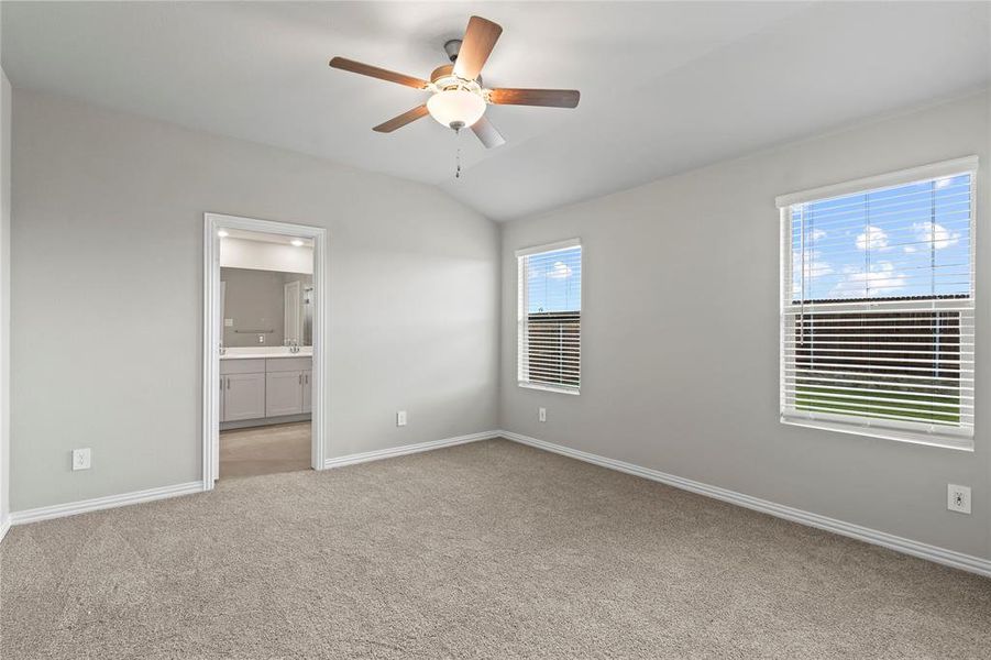 Unfurnished bedroom featuring light colored carpet, ensuite bathroom, lofted ceiling, and a ceiling fan Unfurnished bedroom featuring light colored carpet, ensuite bathroom, lofted ceiling, and a ceiling fan