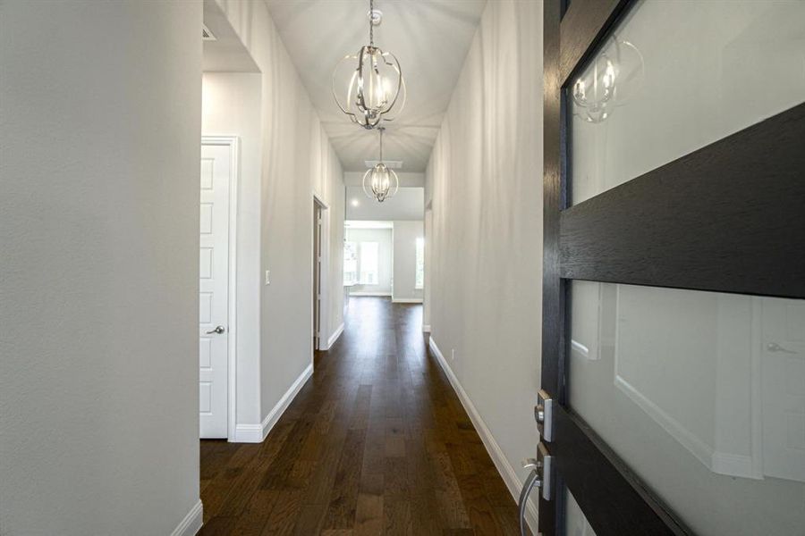 Corridor with an inviting chandelier and dark hardwood / wood-style floors