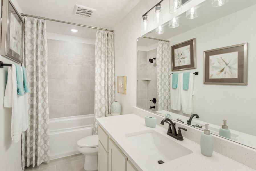 Bathroom with white vanity, large mirror, tub-shower combo, and patterned curtain Bathroom with white vanity, large mirror, tub-shower combo, and patterned curtain