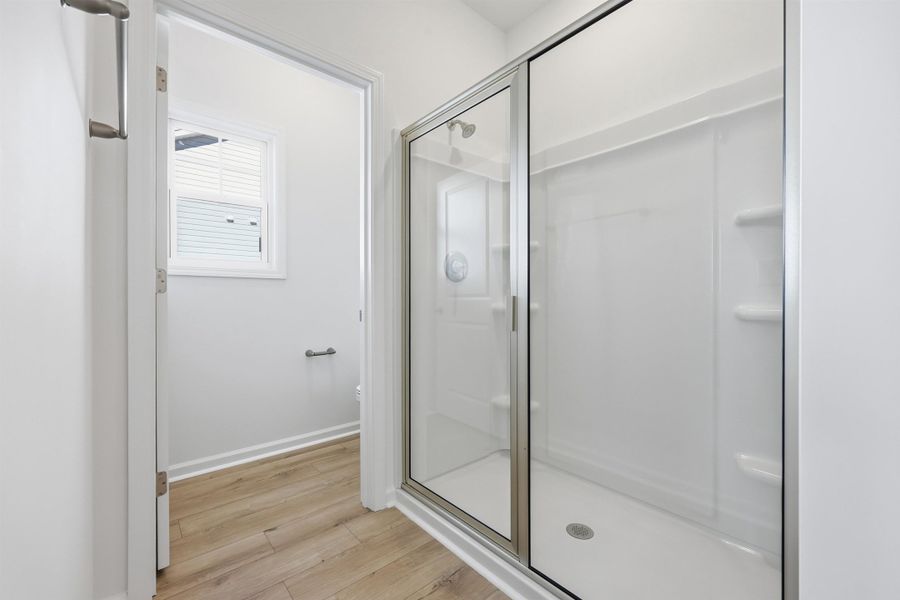 Full bathroom featuring light wood-style flooring and a stall shower Full bathroom featuring light wood-style flooring and a stall shower
