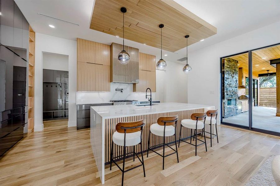Kitchen with modern cabinets, wooden ceiling, a kitchen breakfast bar, light stone countertops, and recessed lighting Kitchen with modern cabinets, wooden ceiling, a kitchen breakfast bar, light stone countertops, and recessed lighting