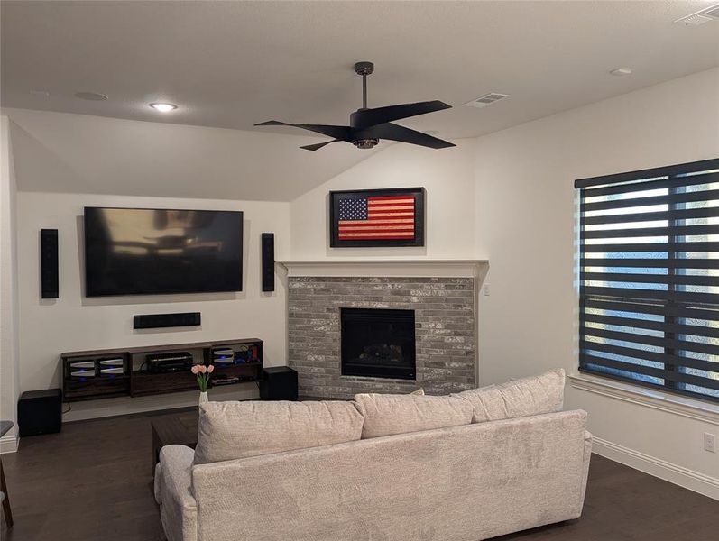 Living room featuring ceiling fan, dark hardwood / wood-style flooring, and vaulted ceiling