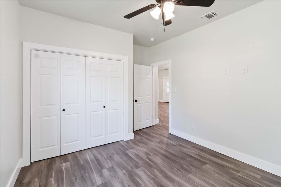 Unfurnished bedroom with wood finished floors, ceiling fan, and a closet