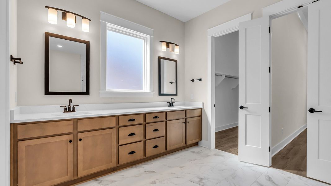 Primary bathroom with large dual vanity and walk-in closet. (Representative of completed home)