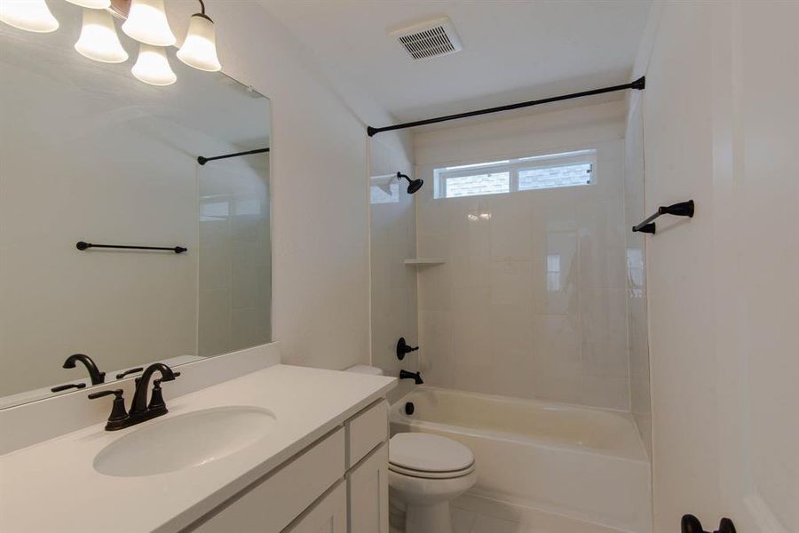 Full bathroom featuring tile patterned floors, toilet, vanity, and tiled shower / bath